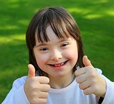 Little girl smiling giving two thumbs up