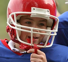 Young boy with football helmet and red sportsguard