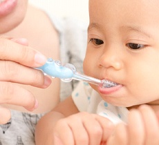 A woman brushing a baby’s teeth