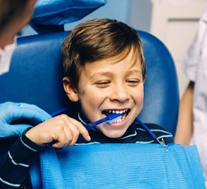 A young boy in the dentist chair with a toothbrush