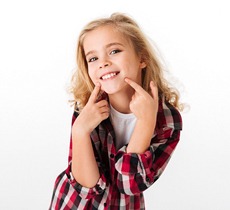A young girl pointing at her smile