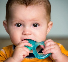 A baby chewing on a teething ring to help while their baby teeth try to erupt