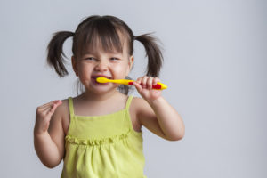 A smiling toddler holding a toothbrush
