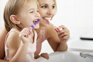 a mom and daughter brushing their teeth