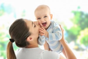 a woman holding and kissing her baby