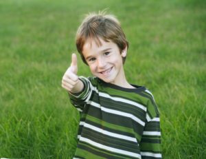 Smiling boy gives thumbs up for dental safety and social distancing
