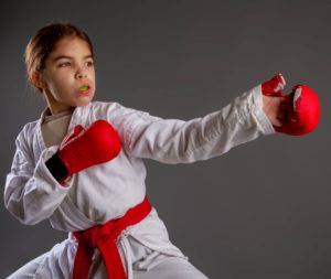 Girl in martial arts clothes with green mouthguard in a fighting stance