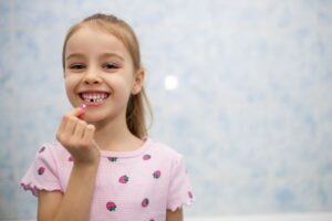 Happy young girl holding her lost tooth 